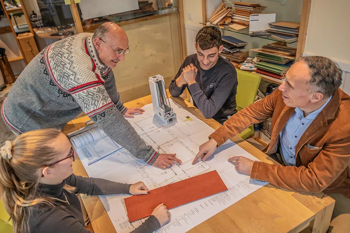 Drei Personen arbeiten als Team an einem Projekt an einem Tisch.