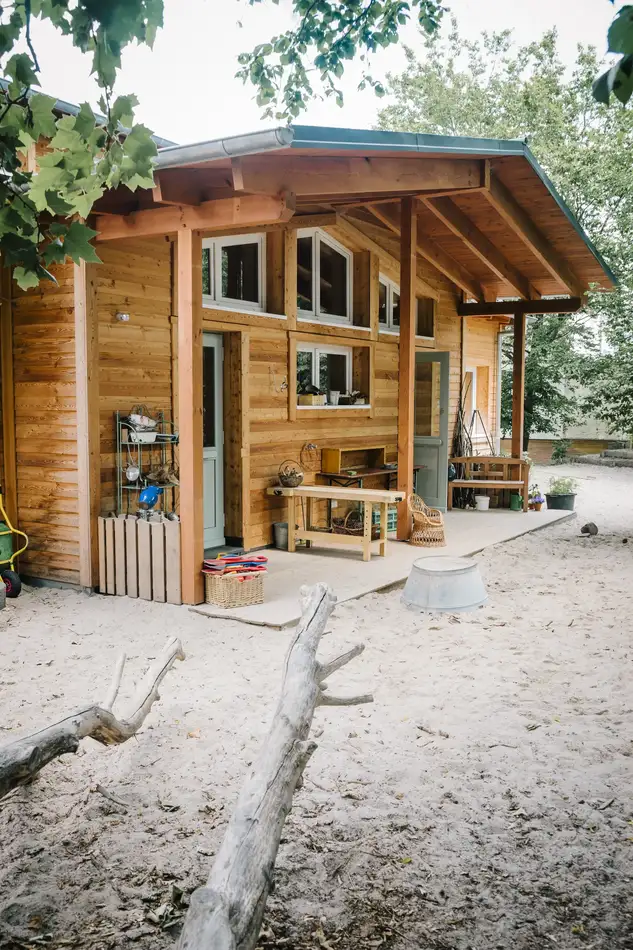 Ein gemütliches Holzhaus mit Veranda und Baumzweige davor.