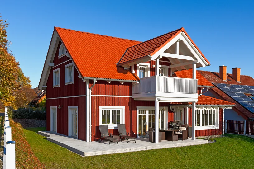 Ein rotes Haus mit einem Solarpanel auf dem Dach.